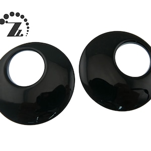 May include: Two black, round, glossy, plastic, decorative pieces with a hole in the center.