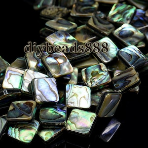 May include: A collection of square-shaped abalone shell beads with iridescent colors of blue, green, and silver. The beads are arranged closely together, with the text "diybeads888" visible.