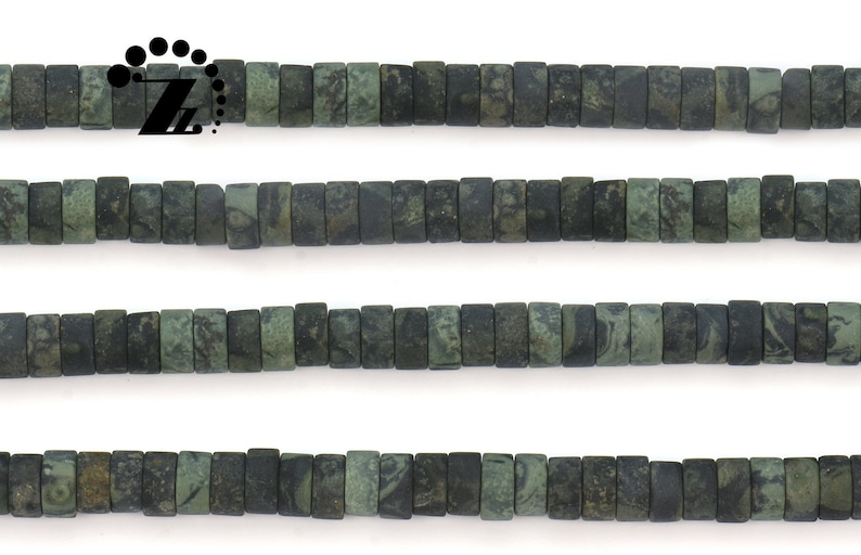 May include: Strands of rectangular, dark green beads with a mottled pattern. The beads are strung together, creating a linear arrangement. The beads are approximately 0.25 inches in length. The beads are likely for jewelry making.