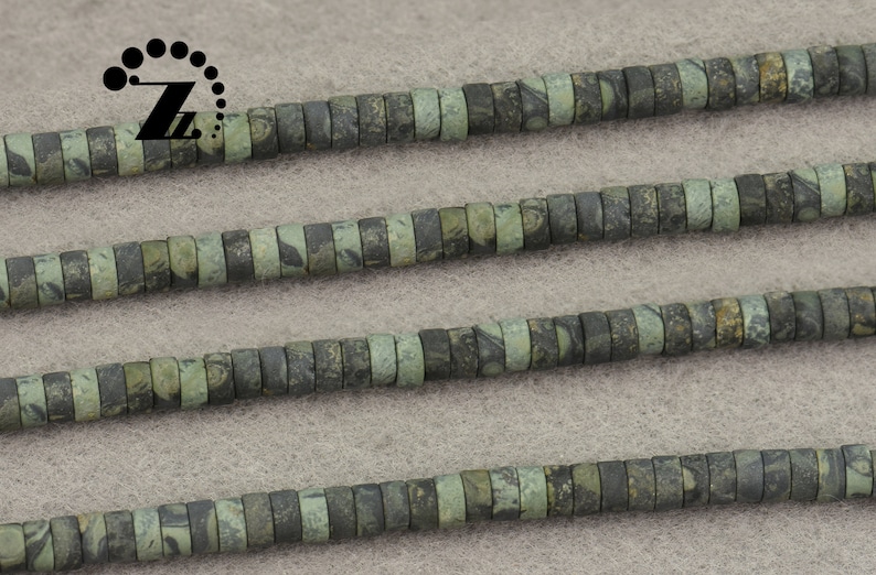May include: Strands of flat, disc-shaped beads in shades of green and gray. The beads have a mottled pattern, creating a natural, earthy appearance. The beads are strung together, suitable for jewelry making or crafting projects.