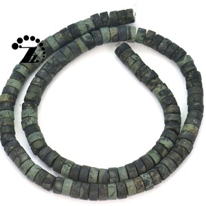 May include: Strand of dark green and black square beads. The beads have a mottled appearance, with variations in color and texture. The beads are strung together, forming a necklace or bracelet. The beads are approximately 0.25 inches in diameter.