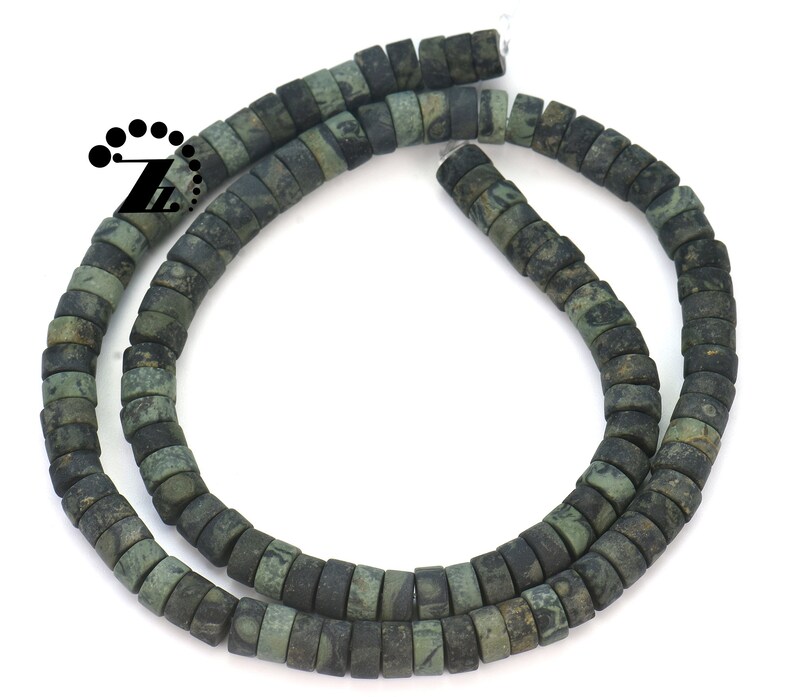 May include: Strand of dark green and black square beads. The beads have a mottled appearance, with variations in color and texture. The beads are strung together, forming a necklace or bracelet. The beads are approximately 0.25 inches in diameter.