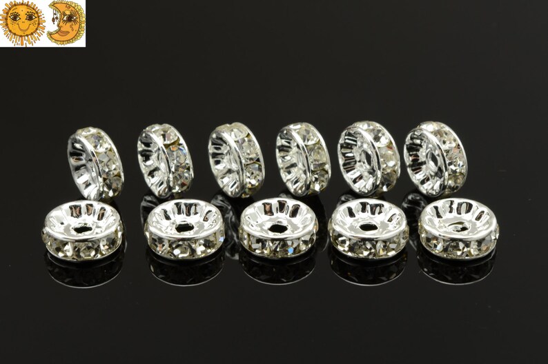 May include: Ten silver-toned bead caps with clear rhinestone accents. The bead caps are round and have a hole in the center.