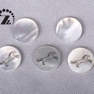 May include: Five white round buttons with a black horse design. The buttons are made of mother of pearl and have a shiny finish.