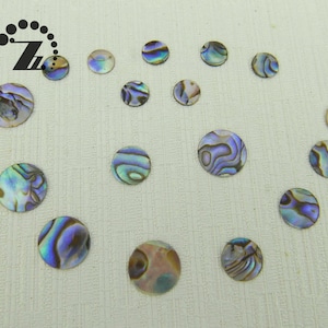 May include: A collection of iridescent, round abalone shell pieces in various sizes. The shells display a range of colors, including blues, greens, and purples, with unique swirling patterns. These decorative shells are ideal for crafting and jewelry making.