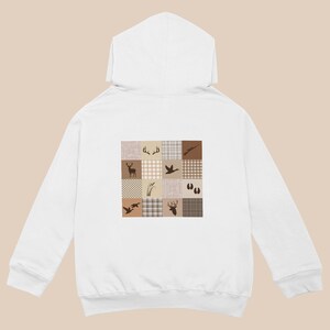 May include: A white hooded sweatshirt featuring a square graphic on the back. The graphic consists of a grid of nine squares with alternating plaid patterns in shades of beige and brown, decorated with silhouettes of deer, antlers, ducks, and tracks.