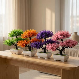Puede incluir: Cuatro bonsáis artificiales en macetas rectangulares de cerámica blanca, dispuestos en fila. Cada árbol presenta un tronco y ramas de color marrón oscuro con un follaje denso y vibrante en verde, naranja, morado y rosa, creando un conjunto colorido.