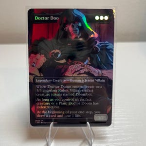 May include: A holographic trading card featuring a dark, hooded figure with a skeletal face. The card text identifies the character as Doctor Doom, a legendary creature, human scientist villain. It includes game rules and a 3/3 power and toughness indicator.
