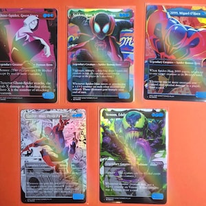 May include: Five rectangular trading cards featuring holographic illustrations of Spider-Man characters including Ghost-Spider, Miles Morales, Spider-Man 2099, Peter Parker, and Venom. Each card displays character names, game text, and blue mana symbols.