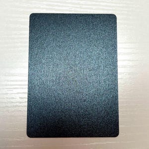 May include: A rectangular card with a dark blue, metallic, and textured finish. The surface has a fine, granular appearance that reflects light across its flat, uniform plane. The edges of the card are rounded, creating a smooth, consistent shape.