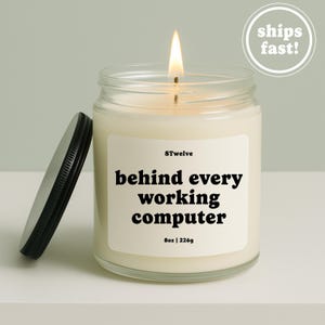 Peut inclure: Une bougie allumée dans un pot en verre transparent avec un couvercle en métal noir. L'étiquette blanche porte le texte 8Twelve, behind every working computer, et 8oz | 226g en noir. La cire est blanc cassé et la flamme est jaune et orange.