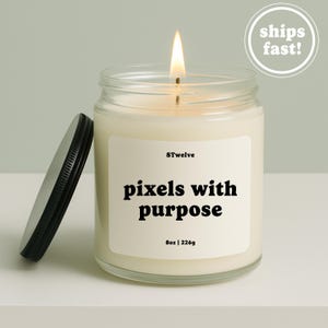 Peut inclure: Une bougie en pot de verre transparent avec une mèche allumée, dotée d'une étiquette blanche portant l'inscription 8Twelve, pixels with purpose, et 8oz | 226g. Un couvercle en métal noir repose à côté de la bougie contenant de la cire blanc cassé.