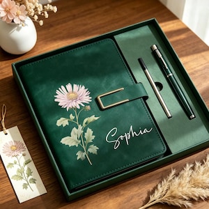 May include: A dark green notebook set featuring a gold-toned metal clasp, a pink chrysanthemum illustration, and the name Sophia in white script. The set includes a matching pen and a bookmark with a floral design, all housed in a green box.