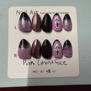 May include: A set of ten almond-shaped press-on nails displayed on a white card labeled Nail Art and Pink Ghost Face. The nails feature black, metallic pink, and solid black finishes, with two nails showcasing a white Ghost Face mask design.