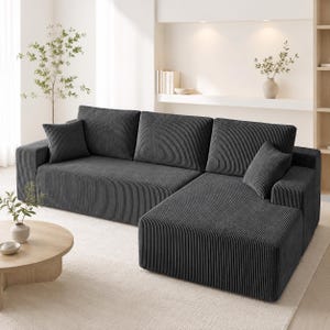 May include: A dark gray sectional sofa upholstered in a textured corduroy fabric. The sofa features a chaise lounge on the right side, three large back cushions, and two square throw pillows, all covered in the same ribbed material.