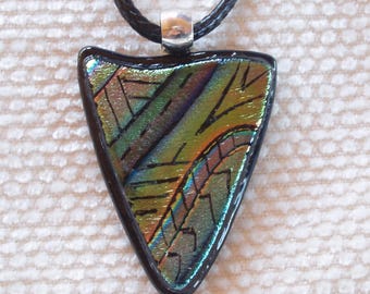 May include: A triangular dichroic glass pendant with a black border, displaying a mix of green, gold, and blue hues. The pendant is suspended from a black cord with a silver-colored clasp, creating a unique and artistic accessory.