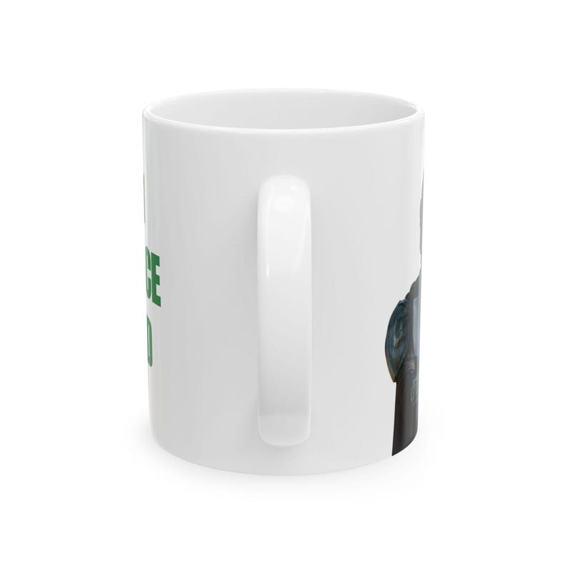 Puede incluir: Una taza de cer&aacute;mica blanca con un asa vertical en el lado derecho. El lateral de la taza muestra el texto en verde "I NOTICE YOU" en letras may&uacute;sculas. A la derecha del asa, se observa una vista parcial de una ilustraci&oacute;n gr&aacute;fica oscura.
