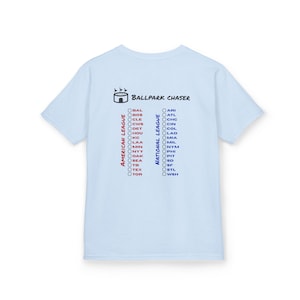 May include: A light blue short-sleeve t-shirt featuring a graphic on the back. The design includes a stadium icon, the text Ballpark Chaser, and two columns labeled American League and National League, each with a checklist of baseball team codes.