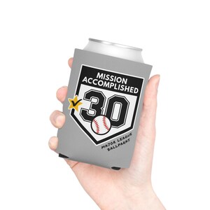 May include: A grey foam can cooler featuring a white home plate graphic with the text MISSION ACCOMPLISHED, the number 30, a yellow star with a checkmark, a baseball illustration, and the text MAJOR LEAGUE BALLPARKS in black lettering.