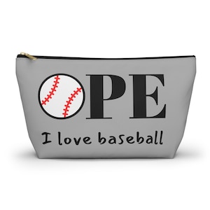 May include: A gray zippered pouch featuring a graphic of a white baseball with red stitching replacing the letter B in the word OPE, printed in large black capital letters. Below, the text I love baseball is written in a smaller black font.