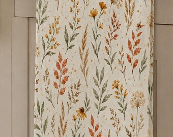 May include: A rectangular kitchen towel featuring a repeating pattern of botanical illustrations including orange, yellow, and green leaves, stems, and wildflowers on a cream-colored background, hanging from a dark metal horizontal towel bar.
