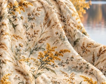 May include: A plush throw blanket featuring a cream-colored base with a repeating botanical print of yellow goldenrod flowers, white daisies, and tall grasses. The fabric has a soft, textured appearance with a dense pile and draped folds.