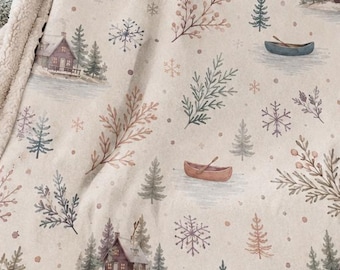 May include: A cream-colored throw blanket with a repeating pattern of small cabins, canoes, evergreen trees, snowflakes, and sprigs of foliage. The blanket features a soft, textured white sherpa fleece lining visible along the folded edge.