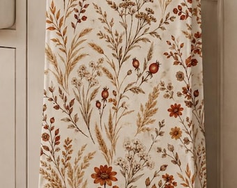 May include: A rectangular kitchen towel featuring a repeating botanical pattern of dried wildflowers, grasses, and berries in shades of rust, orange, brown, and cream. The towel hangs from a black metal handle on a white cabinet door.