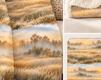 May include: A plush throw blanket featuring a printed landscape of a golden grassy field at sunrise with misty trees in the background. The blanket has a thick, cream-colored sherpa fleece lining on the reverse side and folded edges.