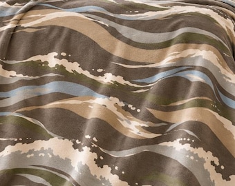 May include: A velveteen blanket featuring a wavy, abstract pattern in shades of brown, olive green, light blue, and cream. The text "Velveteen Blanket" and "Soft statement style for bed or sofa" is printed above the blanket on the wall.