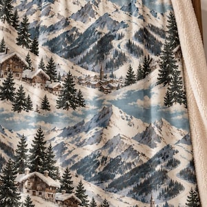 以下が含まれることがあります： 雪に覆われた山頂、常緑樹、小さなアルプスの家々が描かれた冬の山岳風景のプラッシュブランケット。ブランケットの表面は青と白の色調でプリントされており、裏地には厚手のクリーム色のシェルパフリースが使用されています。