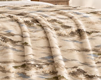 May include: A velveteen plush blanket featuring a cream base with a repeating abstract landscape pattern in shades of muted green, brown, and blue. The text "Velveteen Plush Blanket" and "Lake House Cozy" is printed in the upper right corner.