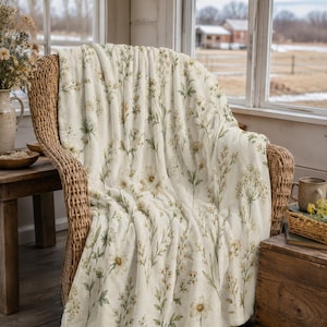 Porch:
Sage and cream floral blanket draped over a farmhouse porch chair with rustic wood and dried wildflowers.