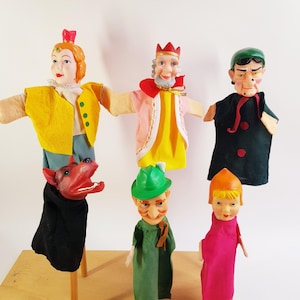 Op de afbeelding: Een verzameling van vijf handpoppen met een personage met een geel vest, een koning met een rode kroon, een heks in een zwarte mantel, een rode wolf en een personage met een groene hoed en roze jurk, allemaal met beschilderde gezichten en stoffen lichamen.
