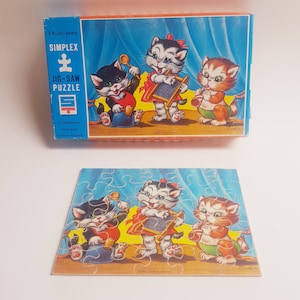 May include: A vintage wooden jigsaw puzzle featuring three kittens playing music. The puzzle box is blue and orange with the words "Simplex Jig-Saw Puzzle" and "Made in Holland".