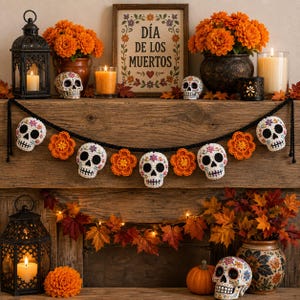 May include: A crochet garland featuring white skulls with colorful floral details and black eye sockets, alternating with bright orange crocheted flowers on a black yarn string, displayed horizontally against a rustic wooden surface.