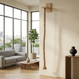 Può includere: Una mensola da parete in legno chiaro dotata di una spessa corda di juta intrecciata color naturale che pende verticalmente dalla parte inferiore. La mensola è rettangolare con angoli arrotondati ed è fissata a una parete interna chiara.