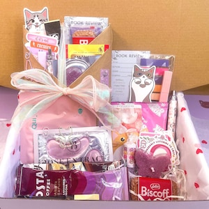 May include: A gift box containing a variety of items including a book review card, a cat sticker, a pink pouch, rose extract eye masks, a Costa coffee packet, a Biscoff biscuit, a butterfly-shaped candle, and a pen, all tied with a sheer ribbon.