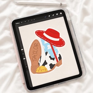 以下が含まれることがあります： タブレット画面上のデジタルイラスト。牛柄模様、青空と白い雲、黄色のつま先キャップが特徴のウエスタンブーツ。ブーツの上には赤い帽子が乗っており、茶色のブーツの靴底にはTAYLORという名前が記されている。