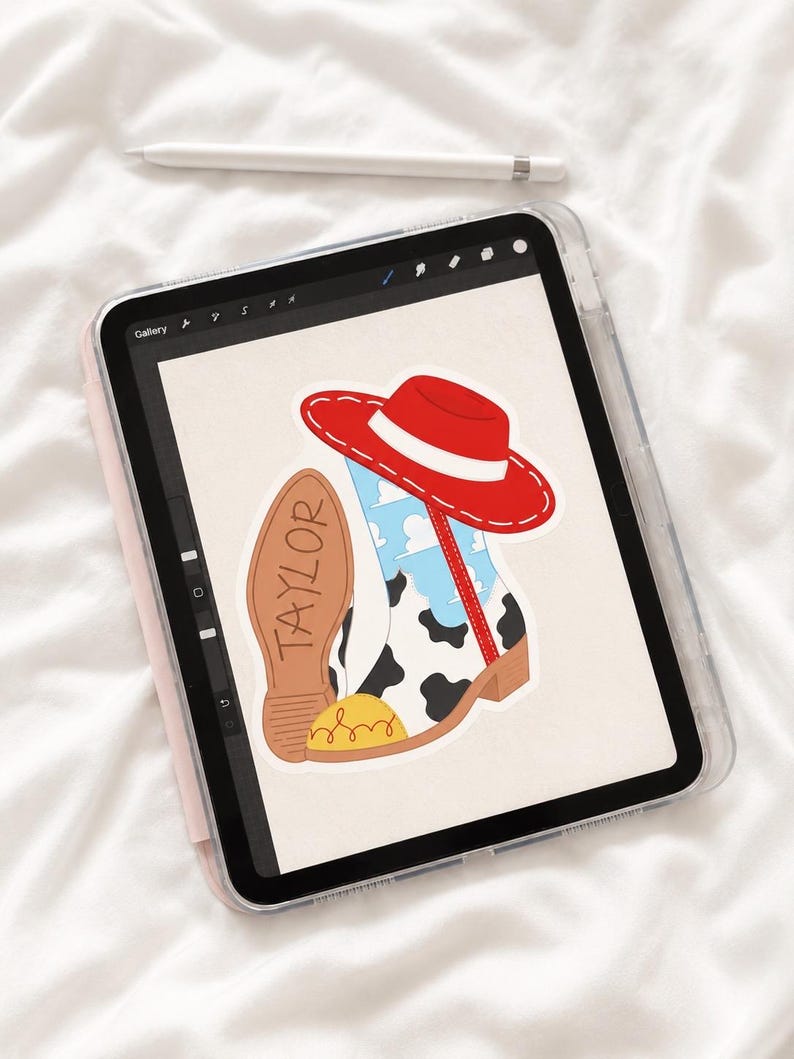 以下が含まれることがあります： タブレット画面上のデジタルイラスト。牛柄模様、青空と白い雲、黄色のつま先キャップが特徴のウエスタンブーツ。ブーツの上には赤い帽子が乗っており、茶色のブーツの靴底にはTAYLORという名前が記されている。