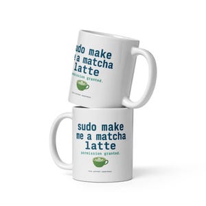 Op de afbeelding: Twee witte keramische mokken verticaal op elkaar gestapeld. De mokken bevatten donkerblauwe tekst "sudo make me a matcha latte" gevolgd door "permission granted." in groene tekst, met een kleine groene afbeelding van een matcha latte eronder.