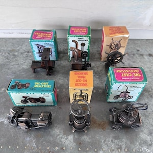 Puede incluir: Una colección de seis sacapuntas en miniatura de metal fundido, cada uno con su caja de cartón. El conjunto incluye modelos de una imprenta, estufa, timón de barco, motocicleta, prensa y carro, todos con un acabado antiguo.