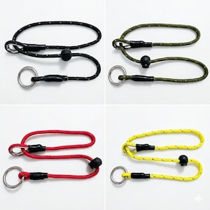 May include: Four adjustable lanyards in black, olive green, red, and yellow, each featuring a durable cord with reflective flecks, a silver-toned metal ring, black plastic heat-shrink tubing at the connection points, and a sliding black cord lock.