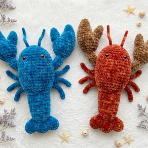 May include: Two plush lobster toys made of soft, velvet-like yarn. One lobster is vibrant blue, and the other is a deep rust-orange with brown claws. Both feature two antennae, two large pincers, multiple legs, and small, dark, round eyes.