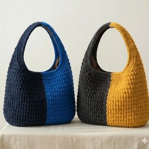 May include: Two hobo-style handbags crafted from thick, textured yarn. The left bag features a vertical color-block design in navy blue and bright blue. The right bag features a vertical color-block design in charcoal gray and mustard yellow.