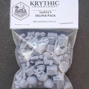 May include: A clear plastic bag containing 100 assorted grey resin miniature pieces. The header card features the text KRYTHIC WORKSHOP, SANTA'S HELPER PACK, and 100 ASSORTED PIECES, along with a small graphic of a skull, mushrooms, and a candle.