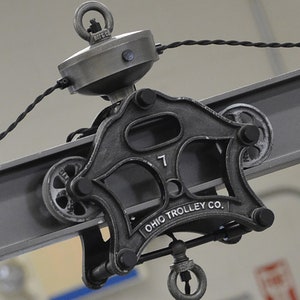 May include: A black metal trolley wheel with the text "OHIO TROLLEY CO." and the number "7" on it. The wheel is attached to a metal beam.