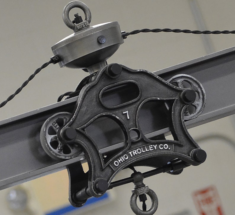 May include: A black metal trolley wheel with the text "OHIO TROLLEY CO." and the number "7" on it. The wheel is attached to a metal beam.