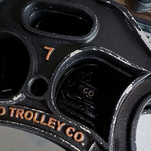 May include: A black metal trolley wheel with the number 7 and the text "O Trolley Co." in gold lettering.
