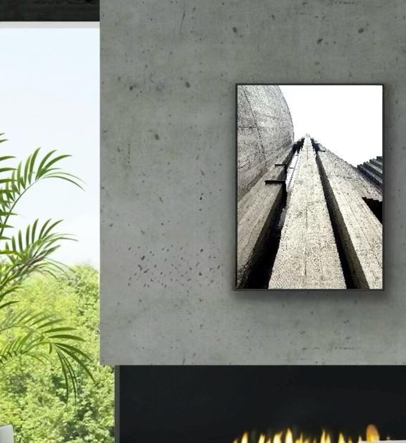 Op de afbeelding: Een rechthoekige wandkunstprint met een zwart-wit architectuurfoto van een gestructureerde betonconstructie. De afbeelding toont een kikkerperspectief van verticale betonzuilen en een gebogen muur, wat diepe schaduwen en lijnen cre&euml;ert.